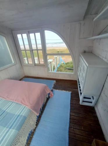 a small room with a bed and a window at Casa beiramar, vista mar e pinheiros, pé na areia in Xangri-lá