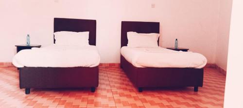 two beds sitting next to each other in a room at Cherika Hotel & Lodgings in Nakuru
