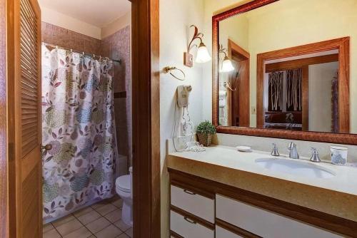 a bathroom with a sink and a toilet and a mirror at Poipu Beach Bungalow in Koloa
