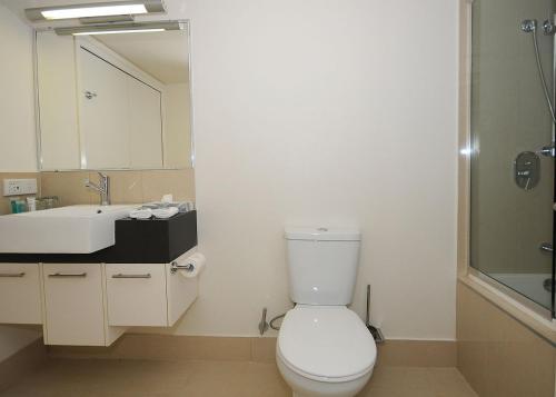 uma casa de banho com um WC, um lavatório e um espelho. em Ramada by Wyndham Hervey Bay em Hervey Bay