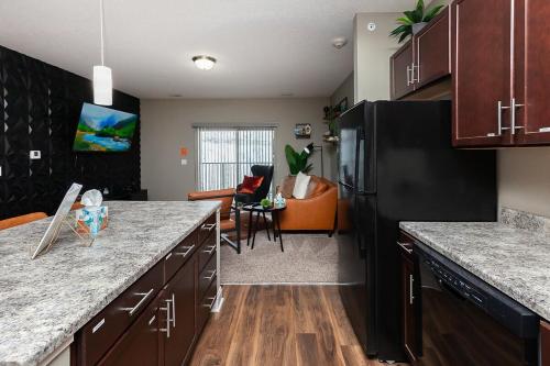a kitchen with a black refrigerator and a living room at Exclusive, Pool, Massage Chair, Jordan Creek in West Des Moines