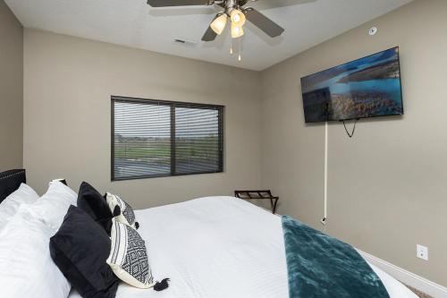 a bedroom with a white bed with a ceiling fan at Stylish & Spacious, Pool, Nintendo Switch, King bed in West Des Moines