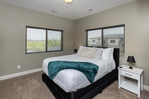 a bedroom with a large bed and two windows at Stylish & Spacious, Pool, Nintendo Switch, King bed in West Des Moines