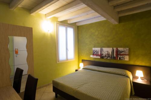 a bedroom with a bed with yellow walls and a window at Al Podestà in Mantova