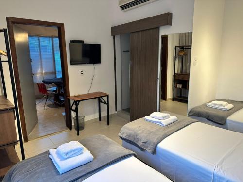 a hotel room with two beds and a television at Kim Casa BH in Belo Horizonte