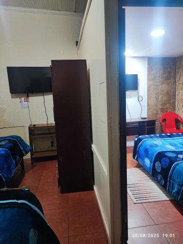 a room with two beds and a door to a bedroom at Hostal Fernanda in Santa Cruz
