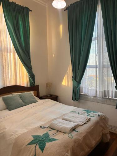 una camera da letto con un letto con tende verdi e asciugamani sopra di Loft Waddington a Valparaíso