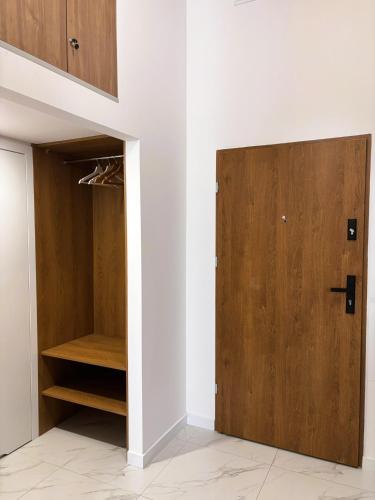 a closet with a wooden door in a room at TINTURA by BAST - Wanna, Antresola, OFF Piotrkowska, EC1 ,Stajnia Jednorożca, Winda, Parking na Terenie, Orientarium, Hopa Lupa, ATLAS ARENA in Łódź