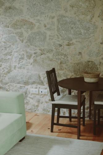 a dining room with a table and chairs and a stone wall at Quinta das Flores in Geraz do Lima