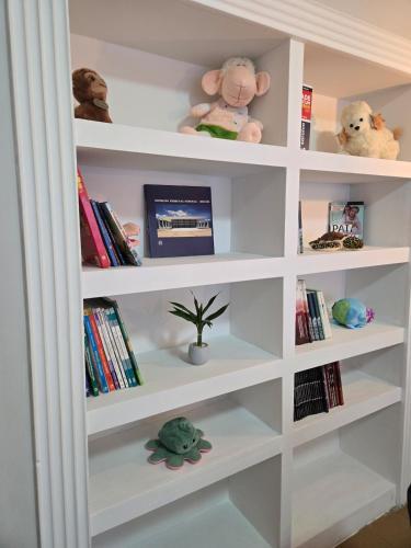 a white book shelf with stuffed animals and books at Elegant House with Party Room in Santana do Livramento