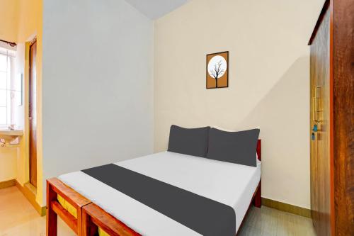 a bedroom with a white bed with a clock on the wall at Super Hotel O Okkilipalayam in Coimbatore