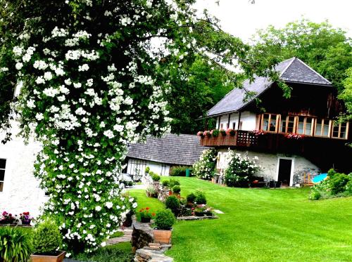 un albero con fiori bianchi di fronte a una casa di Cottage am Waldrand gelegen a Feldkirchen in Kärnten