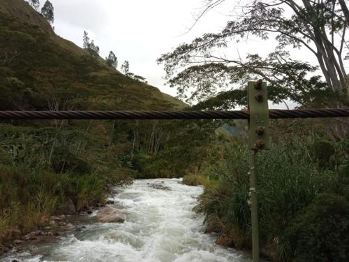 a suspension bridge over a river in a field at Glamping Machupicchu Lodge in Santa Teresa