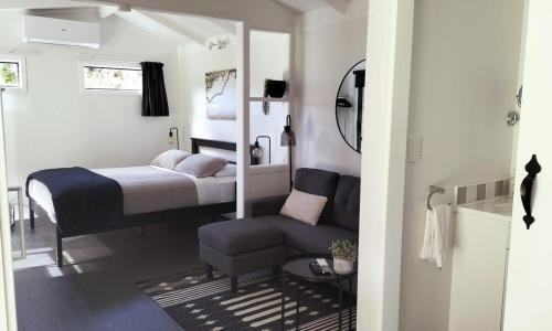 a small bedroom with a bed and a couch at Cosy cottage close to town in Whangarei