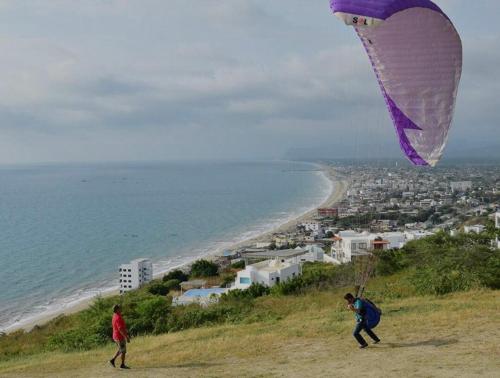 two people flying a kite on a hill near the beach at Dept familiar a pasos de la playa con auto check in in Crucita