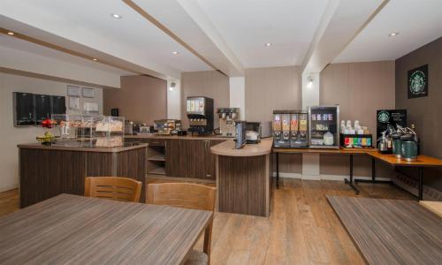 ein Café mit Holztheken, Tischen und Stühlen in der Unterkunft Coast Fort St John Hotel in Fort Saint John