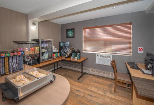 ein Büro mit einem Schreibtisch und einem Tisch und einem Fenster in der Unterkunft Coast Fort St John Hotel in Fort Saint John