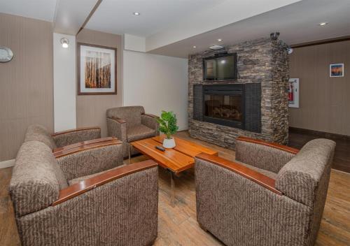 ein Wohnzimmer mit Stühlen und einem Tisch und einem Kamin in der Unterkunft Coast Fort St John Hotel in Fort Saint John