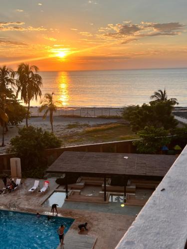 a sunset over the ocean and a swimming pool at Apartamento salida al Mar Santa Marta in Santa Marta