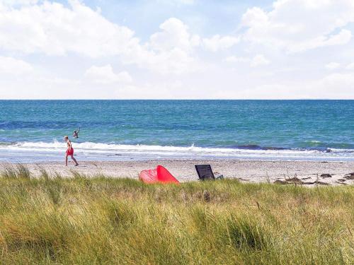 a woman walking on a beach with a person in the ocean at 6 person holiday home in Store Fuglede-By Traum in Store Fuglede