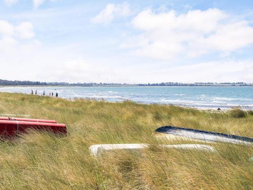 a beach with a bench in the grass next to the water at 6 person holiday home in Store Fuglede-By Traum in Store Fuglede