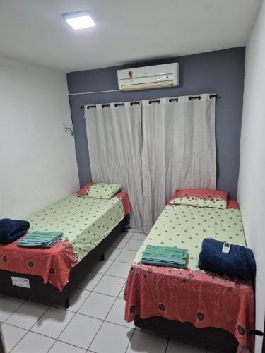 two beds in a room with two tables at Apartamento completo Corumbá in Corumbá