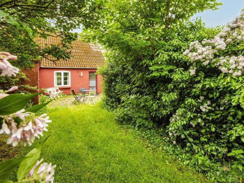 a garden with a red house and some bushes at 6 person holiday home in Bredebro in Bredebro