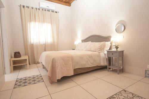 Ioppolo GiancaxioにあるLe case del Ducaの白いベッドルーム(ベッド1台、鏡付)