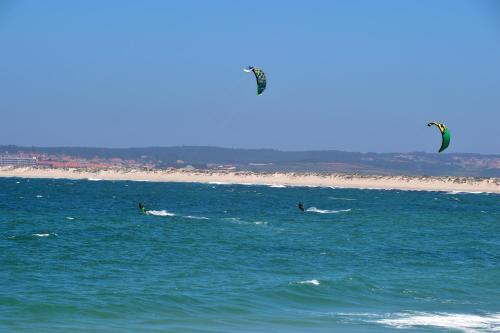 two people kite surfing in the ocean on the beach at Mercearia D'Alegria Boutique B&B in Peniche
