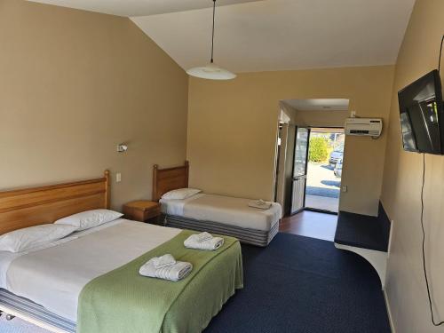 a hotel room with two beds and a tv at Karamea Hotel in Karamea