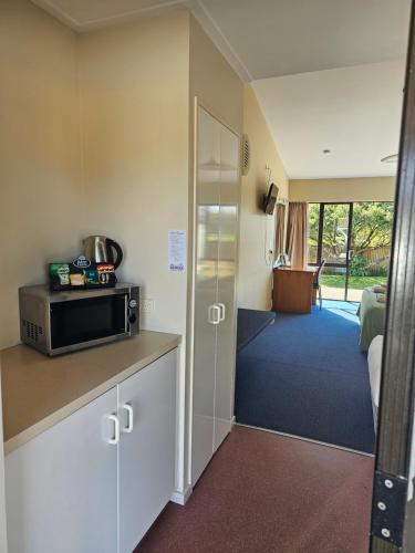 a room with a kitchen with a microwave and a living room at Karamea Hotel in Karamea