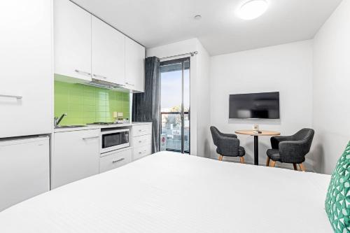 a kitchen with white cabinets and a table with chairs at Quality Apartments North Melbourne in Melbourne