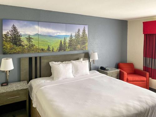 a hotel room with a large bed and a red chair at Clarion Pointe - Greensboro Coliseum Area in Greensboro