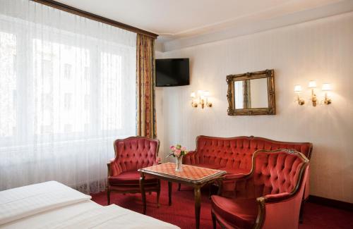 a hotel room with red chairs and a table and a mirror at Pension Suzanne in Vienna
