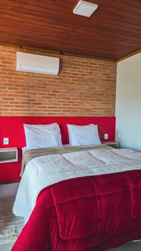 a large bed in a room with a brick wall at Chales Vidal in Venda Nova do Imigrante
