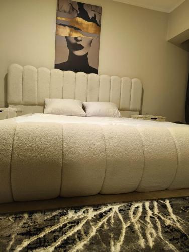 a large white bed in a room with a painting at شقة على النيل مباشر بالمعادى 3 غرف الدور 31 فيو الاهرامات in Cairo