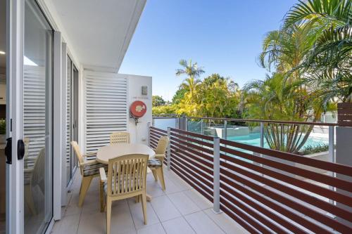 a balcony with a table and chairs and palm trees at Waterline 102 in Forster