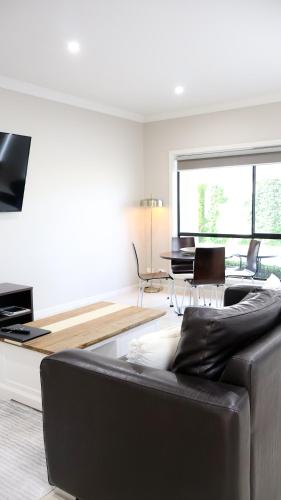 a living room with a black couch and a table at Renmark Holiday Apartments in Renmark