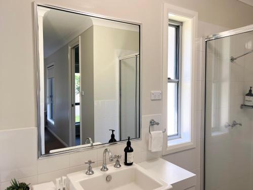 a white bathroom with a sink and a mirror at Boorooma Bliss in North Wagga