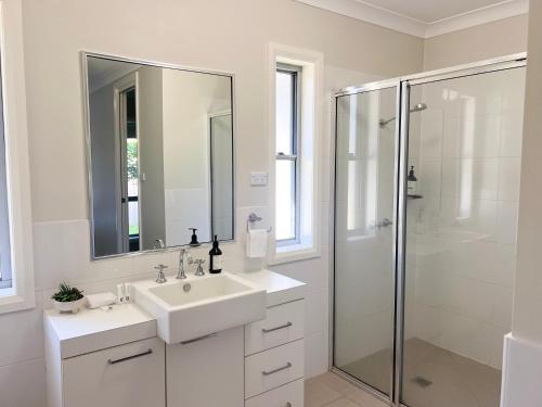 a white bathroom with a sink and a shower at Boorooma Bliss in North Wagga