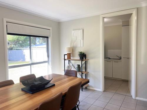 a dining room with a wooden table and chairs at Boorooma Bliss in North Wagga