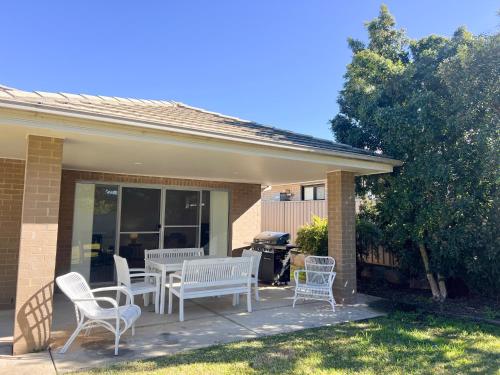 a patio with white chairs and a table and a grill at Boorooma Bliss in North Wagga