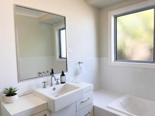a white bathroom with a sink and a mirror at Boorooma Bliss in North Wagga
