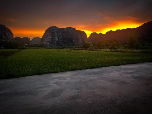 a sunset over a field with mountains in the background at Sol Flow Retreat in Nguyên Ngoại