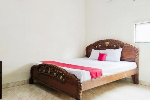 a bedroom with a wooden bed with a red blanket at Turuo Homestay Syariah Pringsewu Lampung Mitra RedDoorz in Margakaya