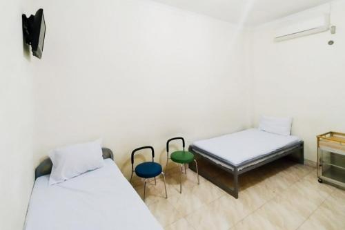 a room with two beds and two chairs in it at Turuo Homestay Syariah Pringsewu Lampung Mitra RedDoorz in Margakaya