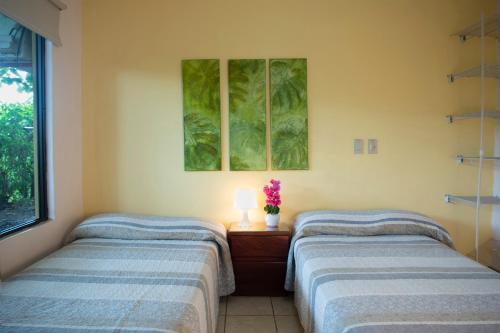 a room with two beds and a table with a lamp at Apartments-Villas Playa Potrero 1 in Potrero