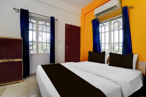a bedroom with a large bed with blue curtains at Super Hotel O Palarivattom Metro Station Formerly South Gate in Edappally