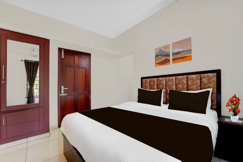 a bedroom with a large bed and a window at Super Collection O Valiyavila Junction Formerly Prism Heights in Trivandrum