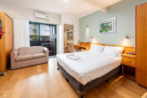 a bedroom with a bed and a chair in it at Boat Harbour Apartments Studio in Urangan